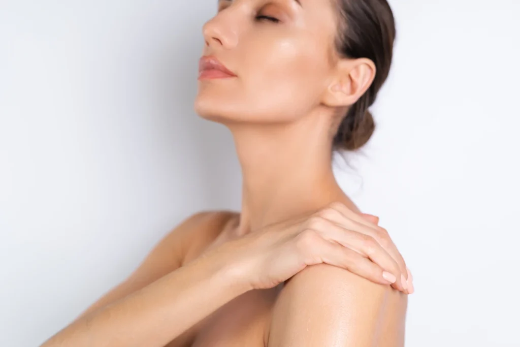 Close beauty portrait of topless woman with perfect skin holding bottle
